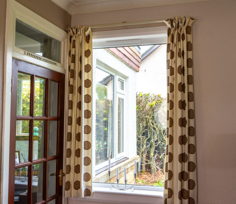 Internal view of a Lorimer casement window in Falkland, situated in the living room. The window is complete with gold handles and a painted white sill and surround.